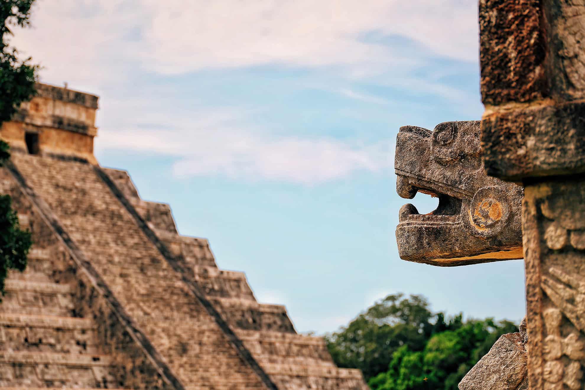 Close-up of stone carved dragon head with view of stone temple with steep steps in the background