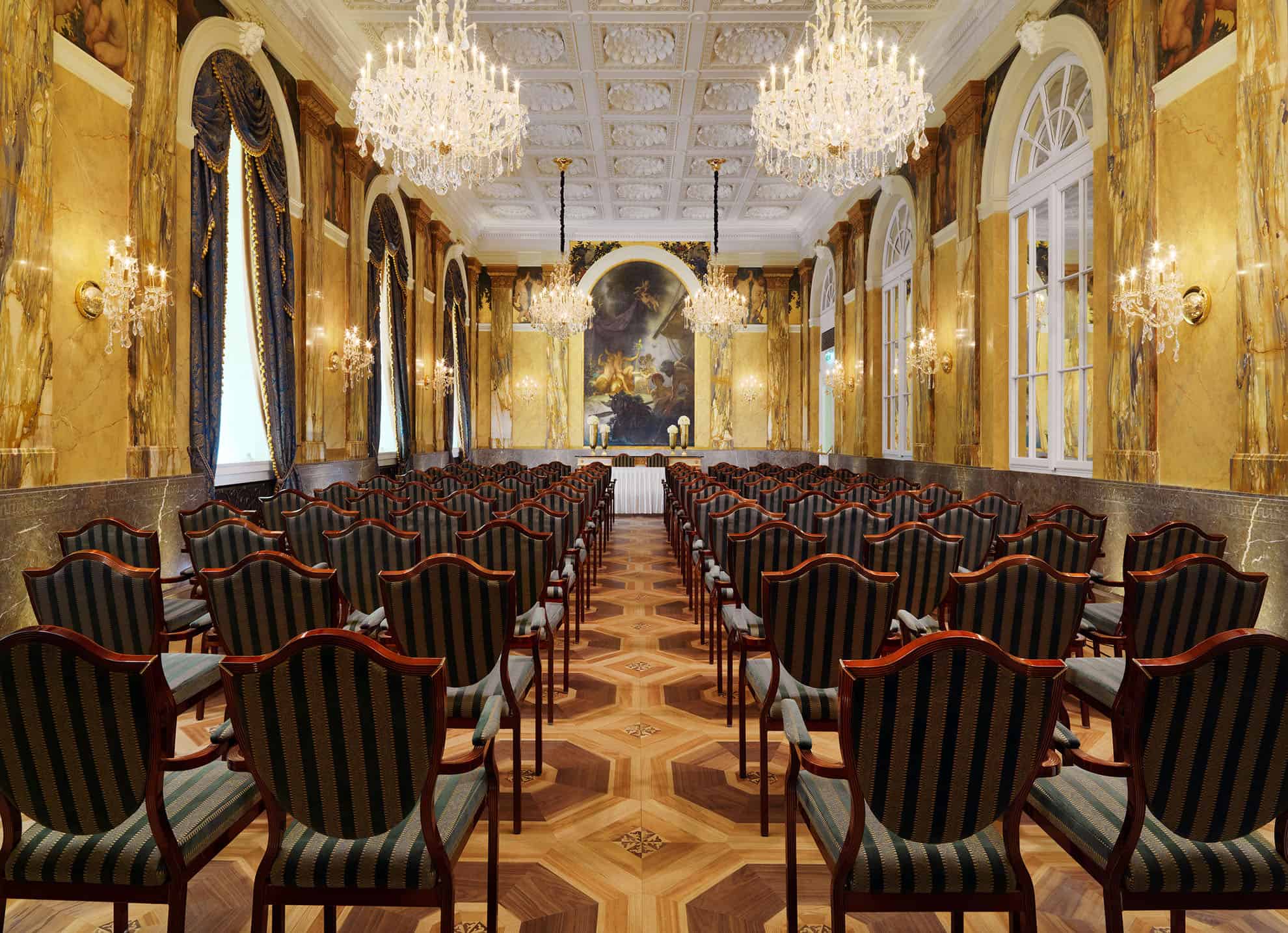 Sala de reuniones larga con ventanas arqueadas, cortinas de terciopelo y candelabros de cristal