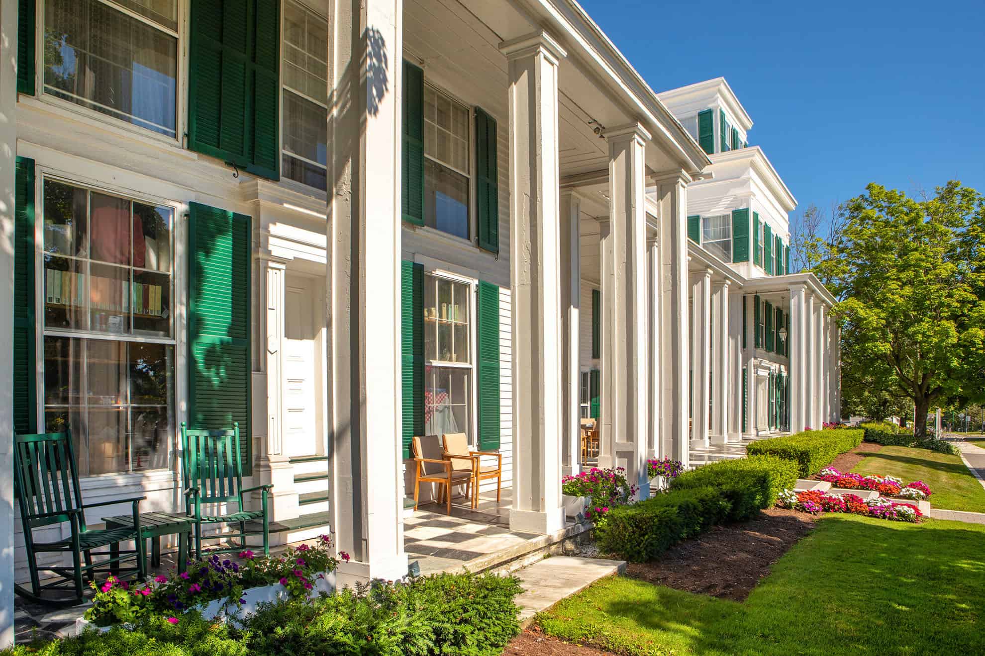 Row of townhome style buildings with tall pillars and seating on the front porch
