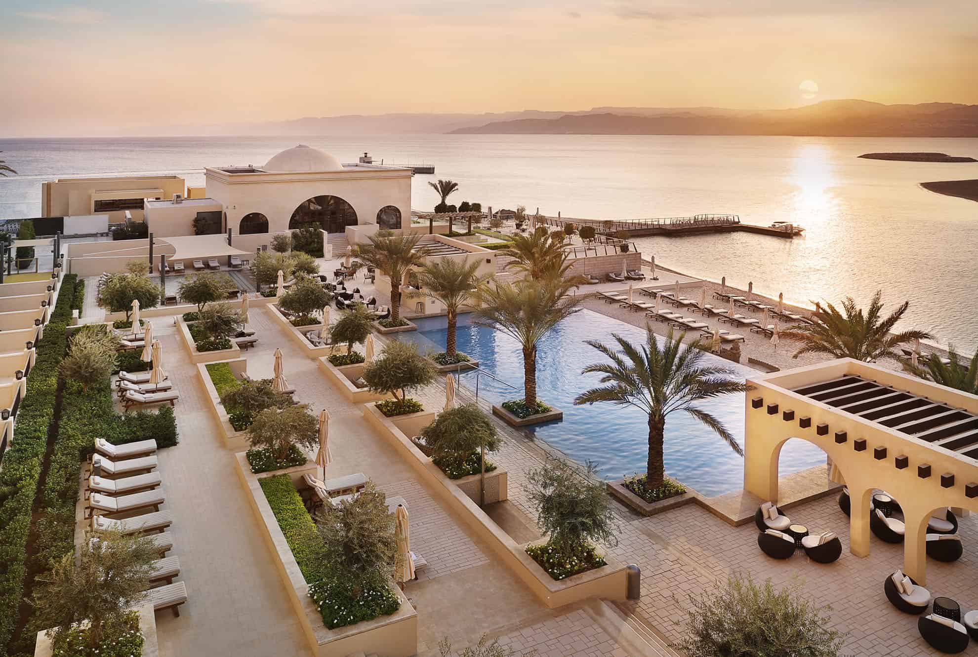 Waterside resort pool with tropical flora, loungers and umbrellas