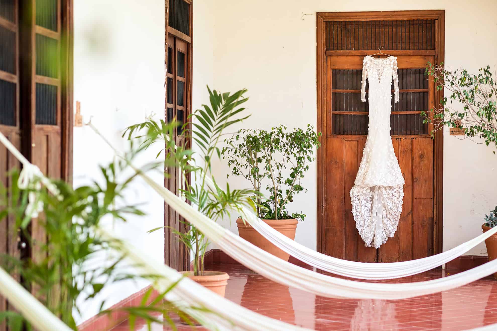 Vestido de novia de encaje blanco cuelga de una puerta situada al final de un salón acordonado