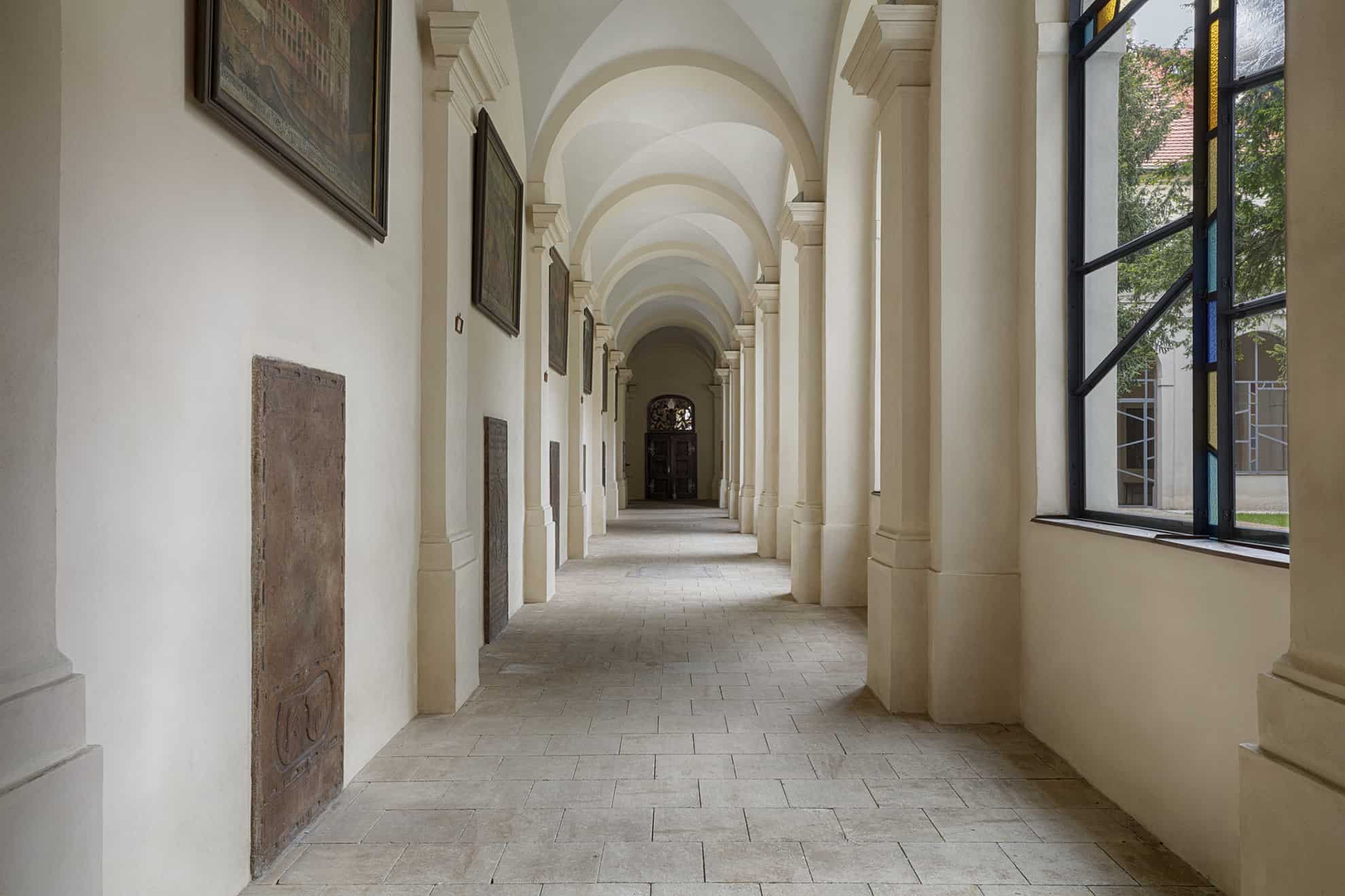 Long white hall with arched ceiling and dark door at end