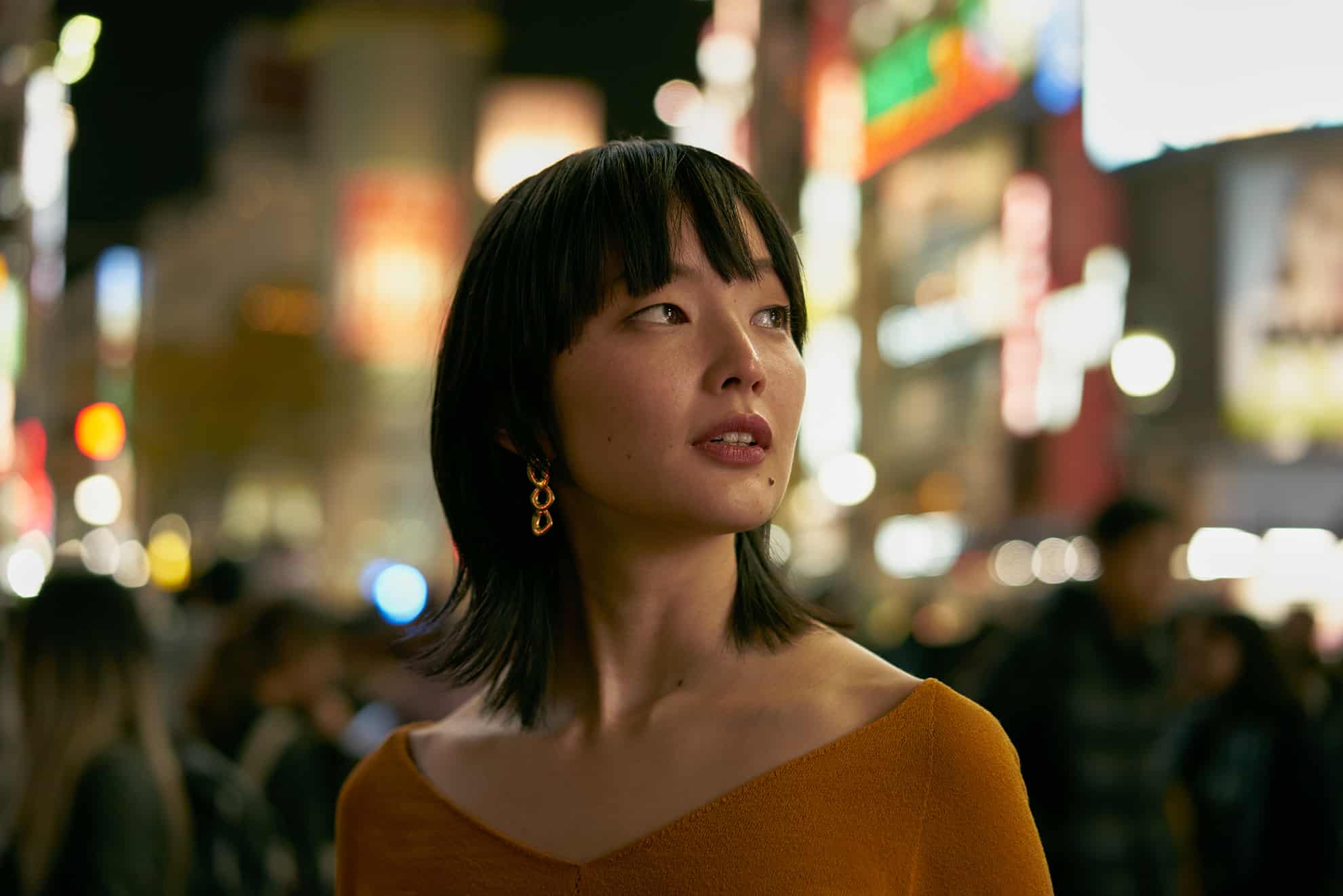 Close-up of woman looking to the side with a busy city street scene blurred in the background