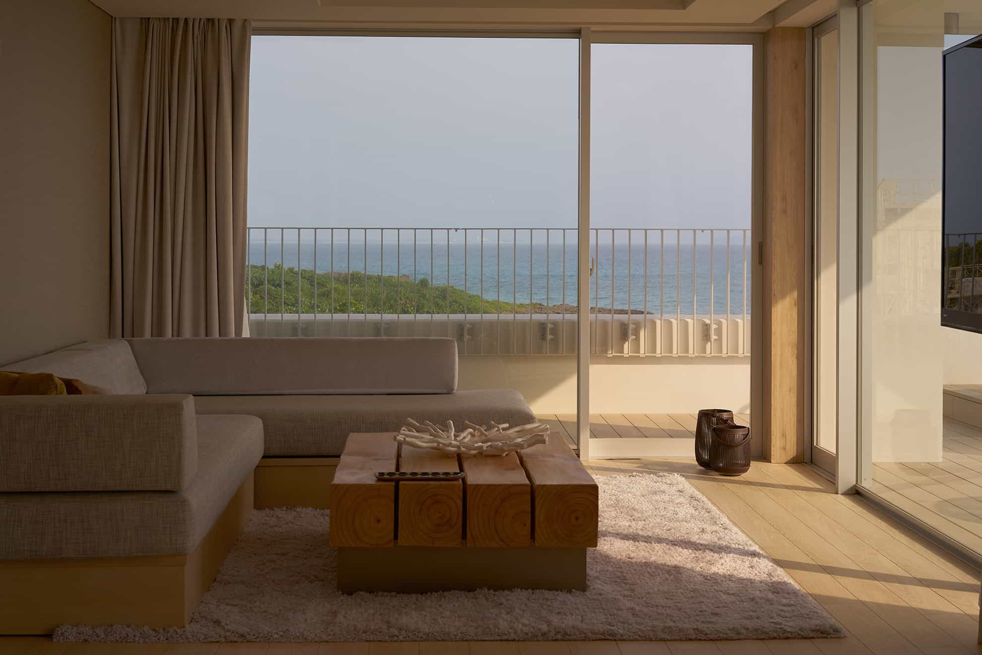 Suite living room with sectional sofa aside wall of windows with ocean view and sliding patio door