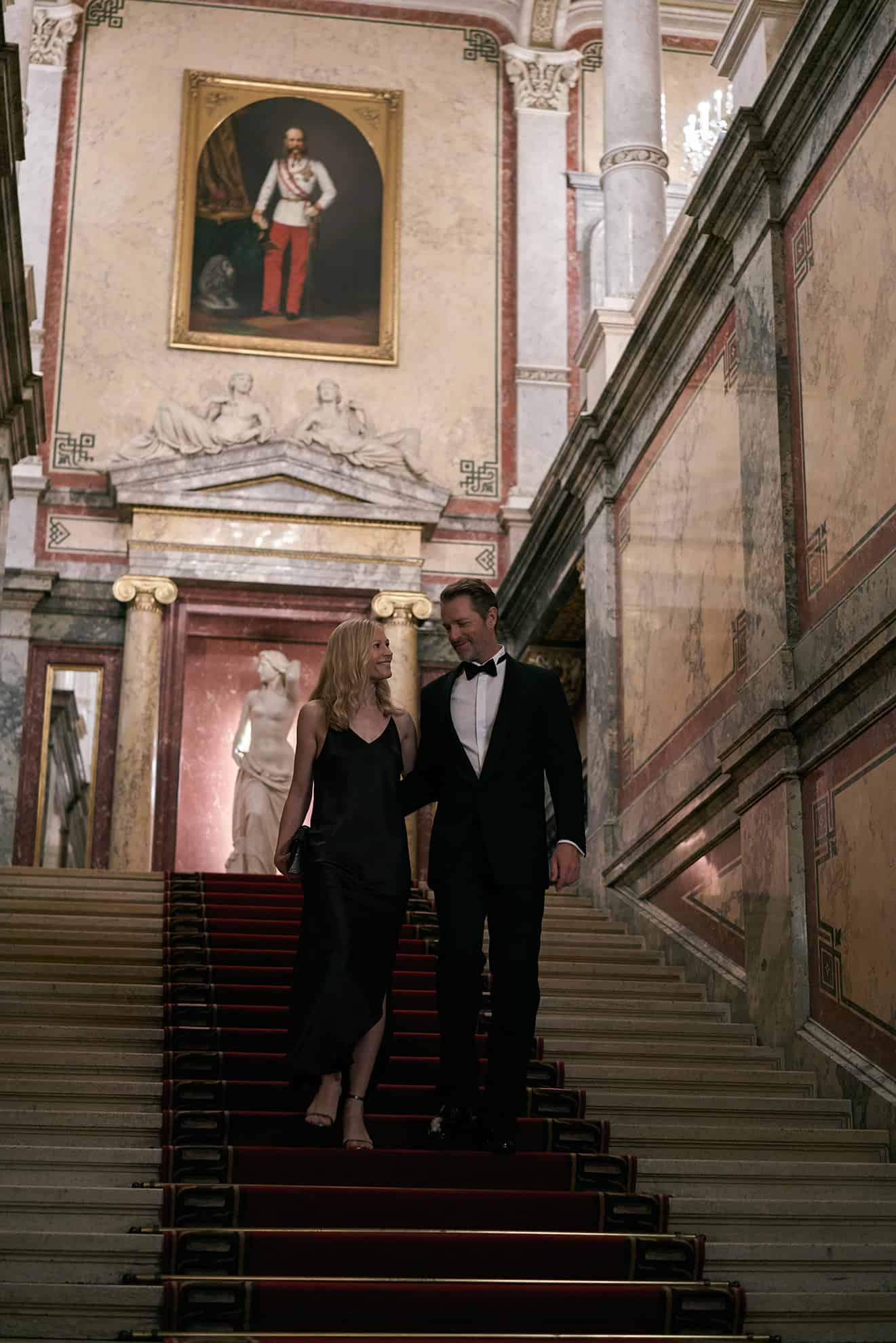 Formally dressed couple walking down steps and looking at each other