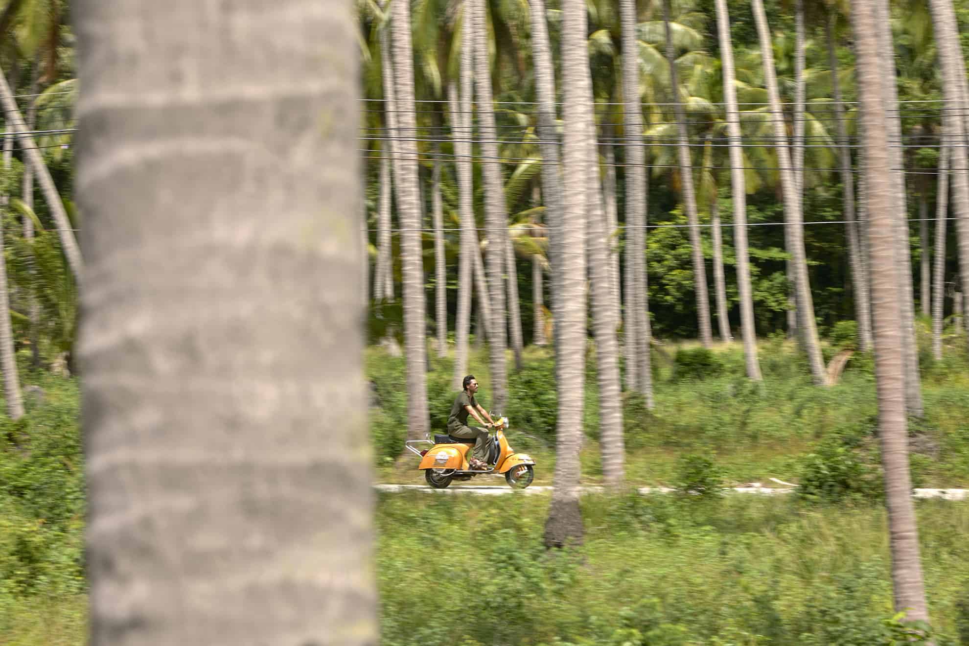 Man riding vespa through tropical forest road