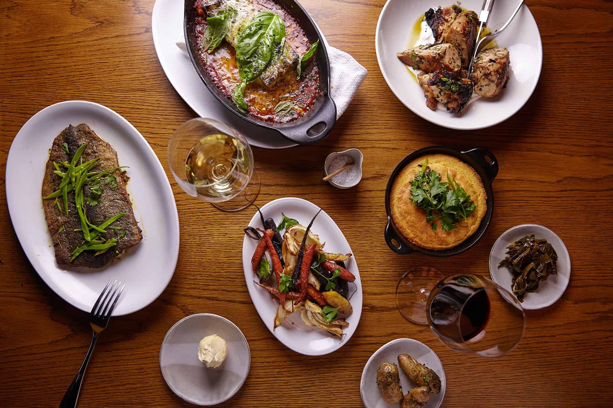 Overhead view of several plated dishes and two glasses of wine on a table