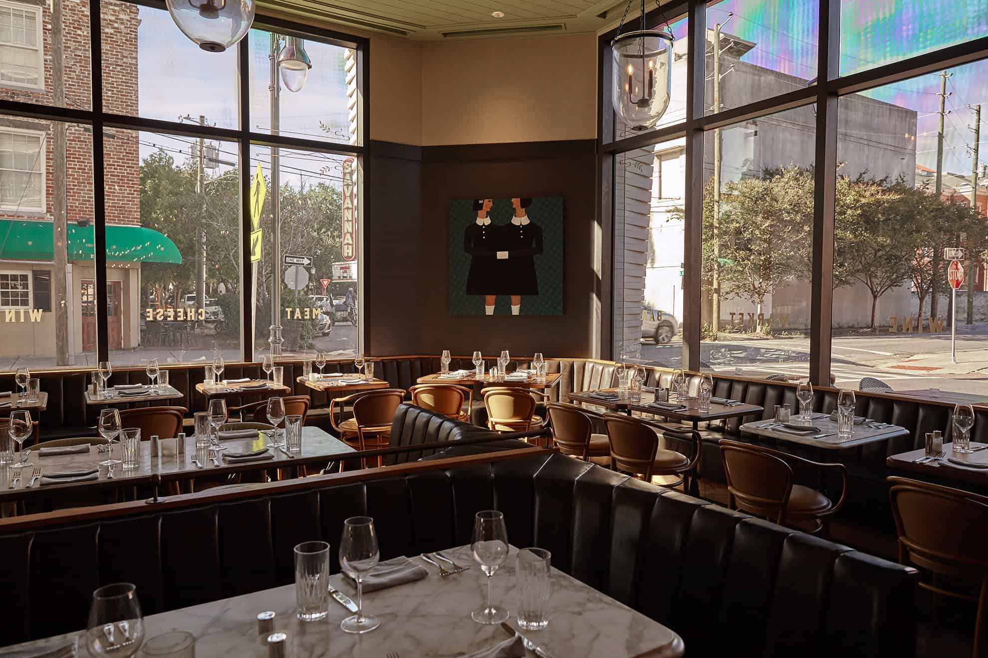 Corner view of restaurant with banquette seating, marble tabletops & large city view windows