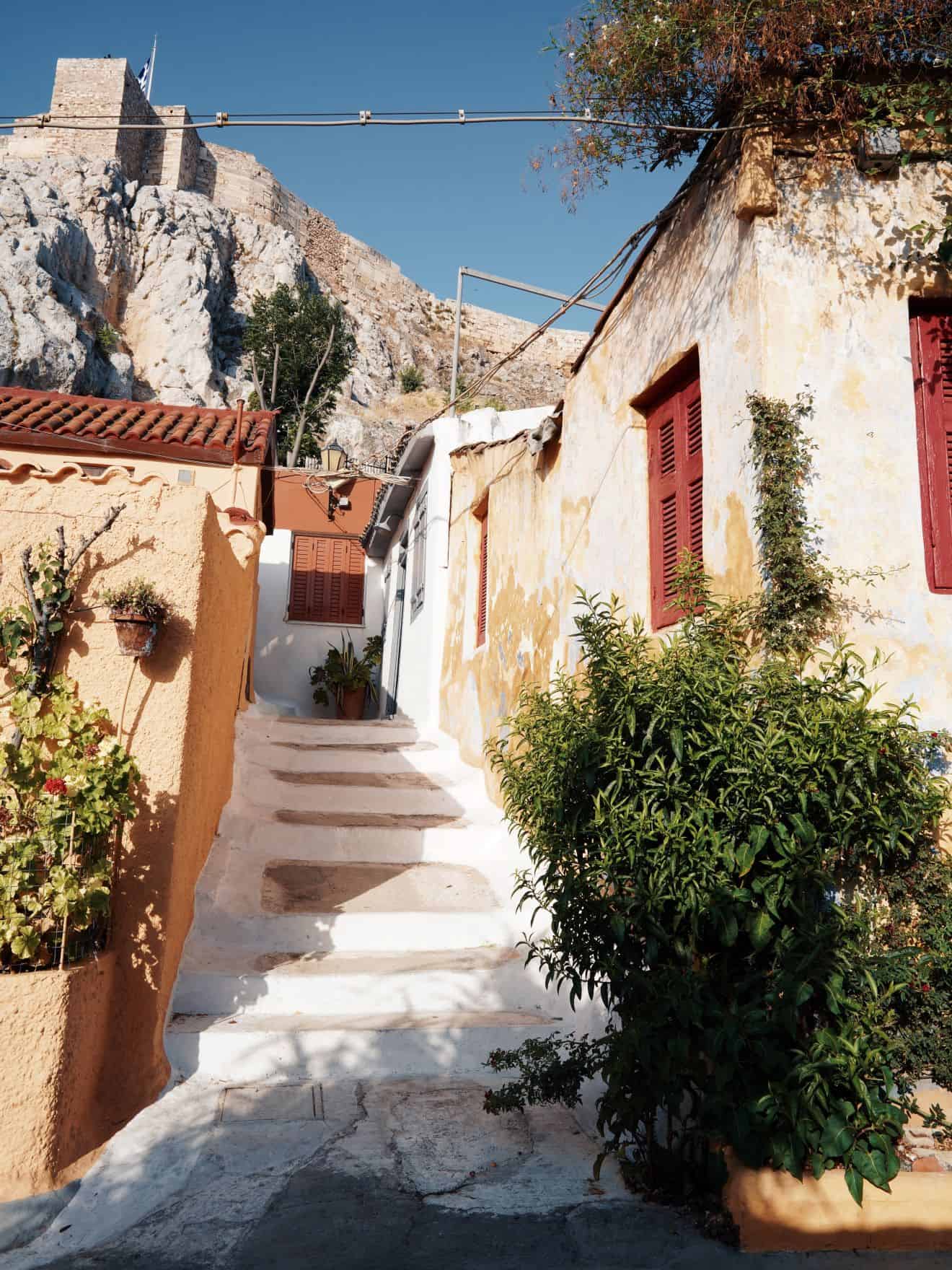 Stone walkway between quaint buildings with historic building atop hill in background
