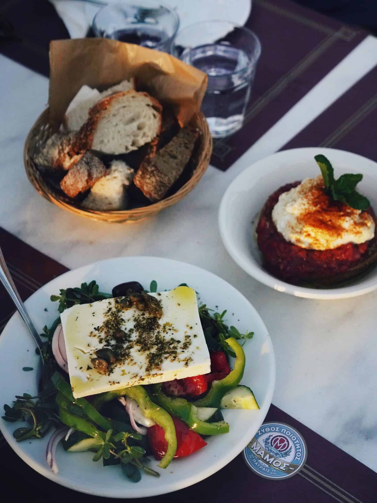Beautifully plated vegetables with cheese and herbs on table with basket of bread