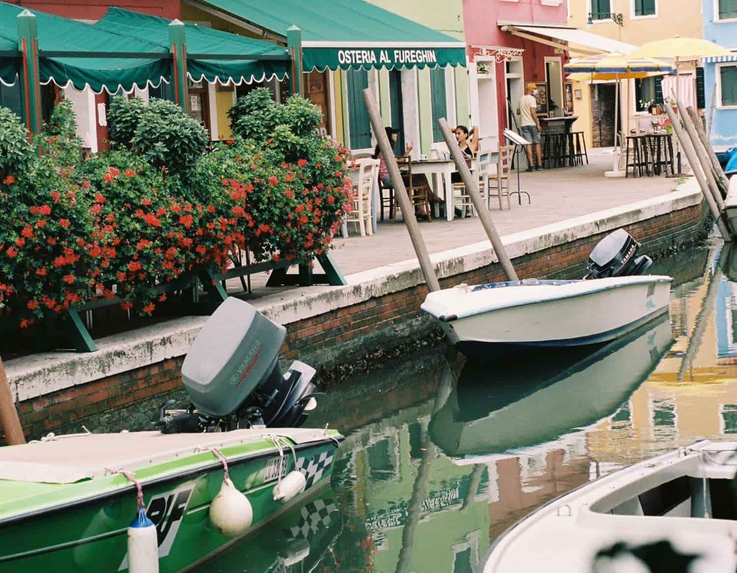 Canal with boats along brick walkway with colorful buildings