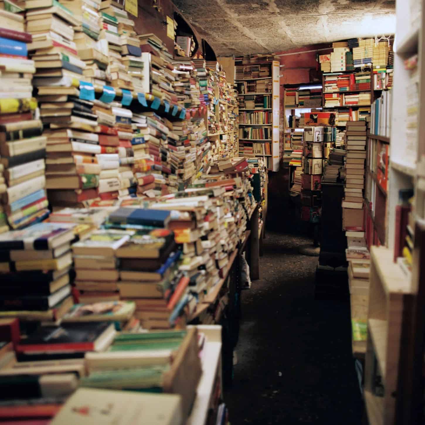 Bookstore overflowing with stacks of books on shelves and tables