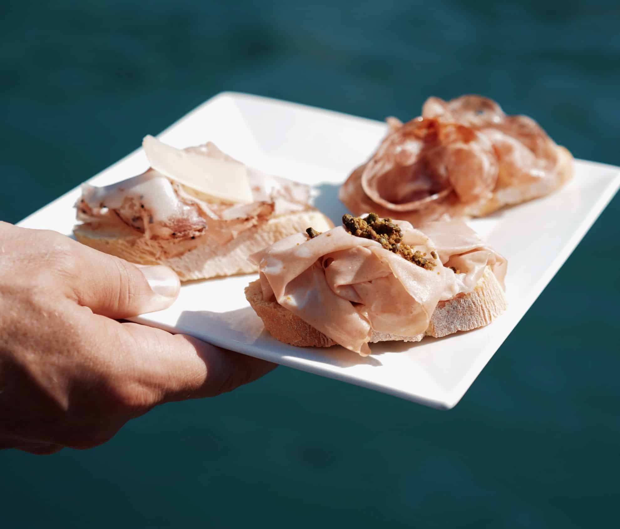 Hand holding square plate with crostini