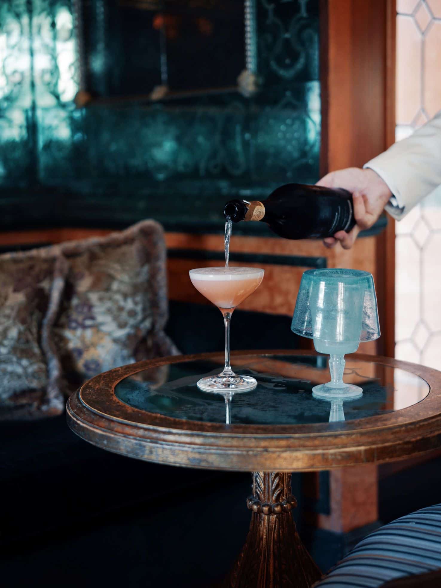 Small wood and marble table with glass of champagne being poured
