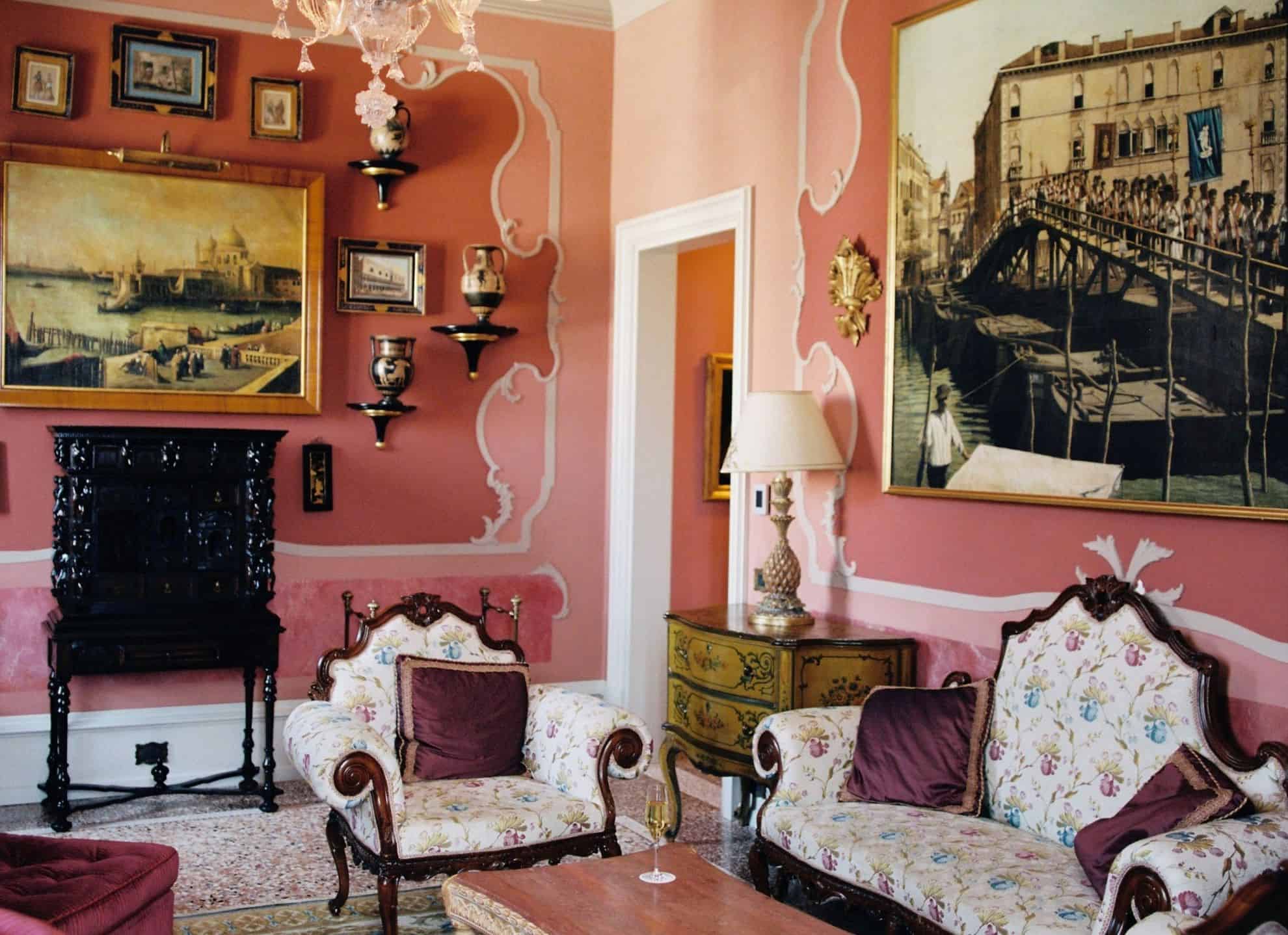 Parlor with romantic pink walks, chandelier, seating area and framed artwork