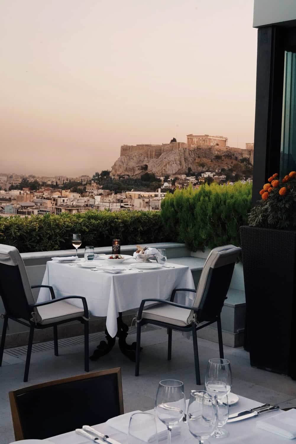 Outdoor dining area overlooking a town with cliffs in the distance