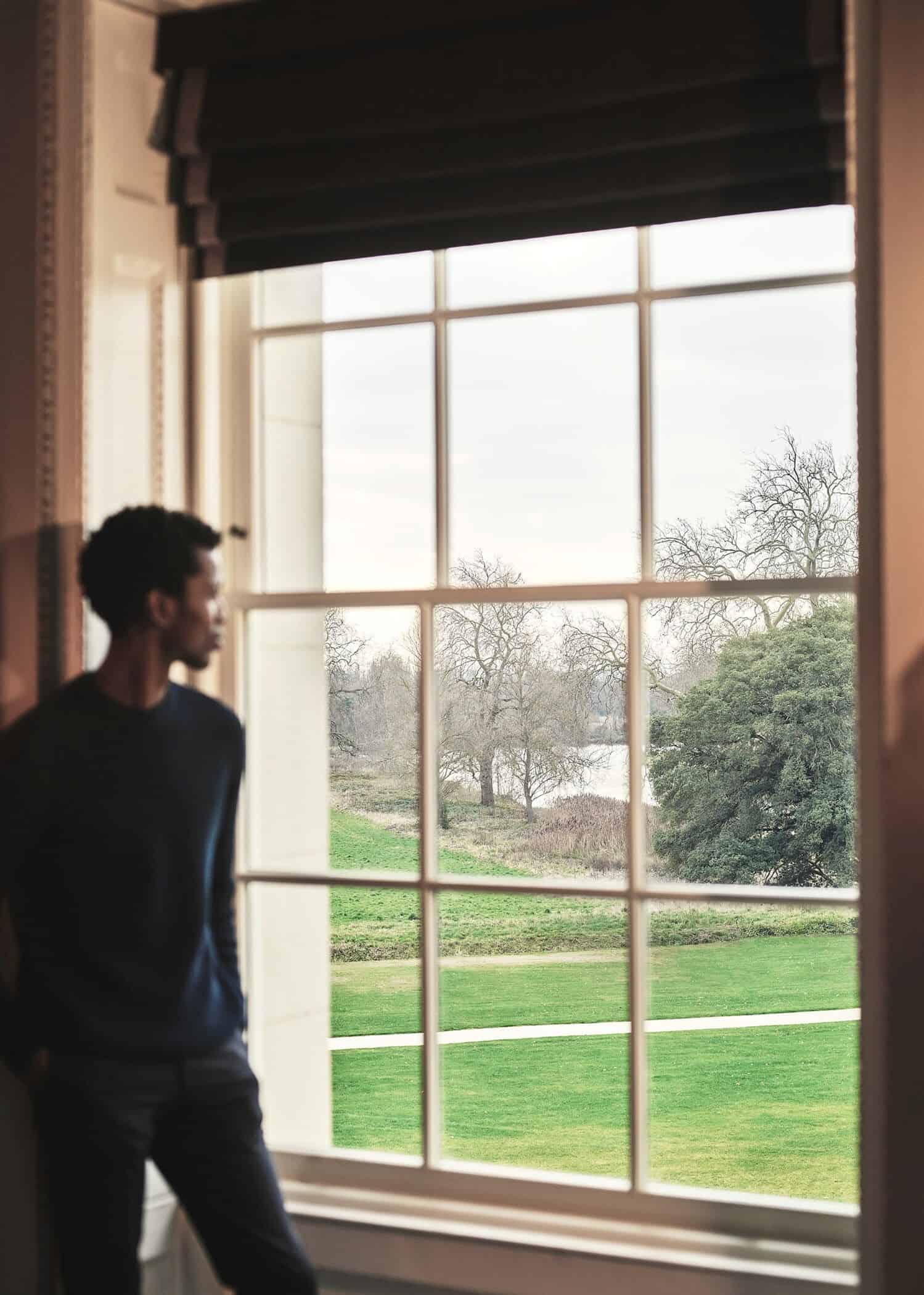 Man looking out large window at green lawn