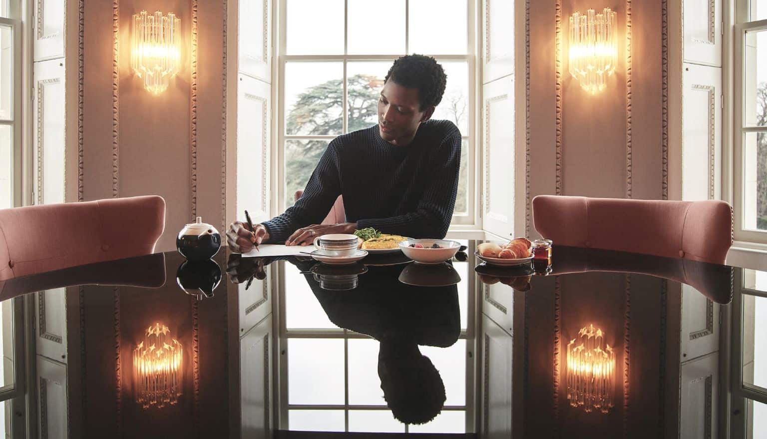 Man at table writing note and eating breakfast