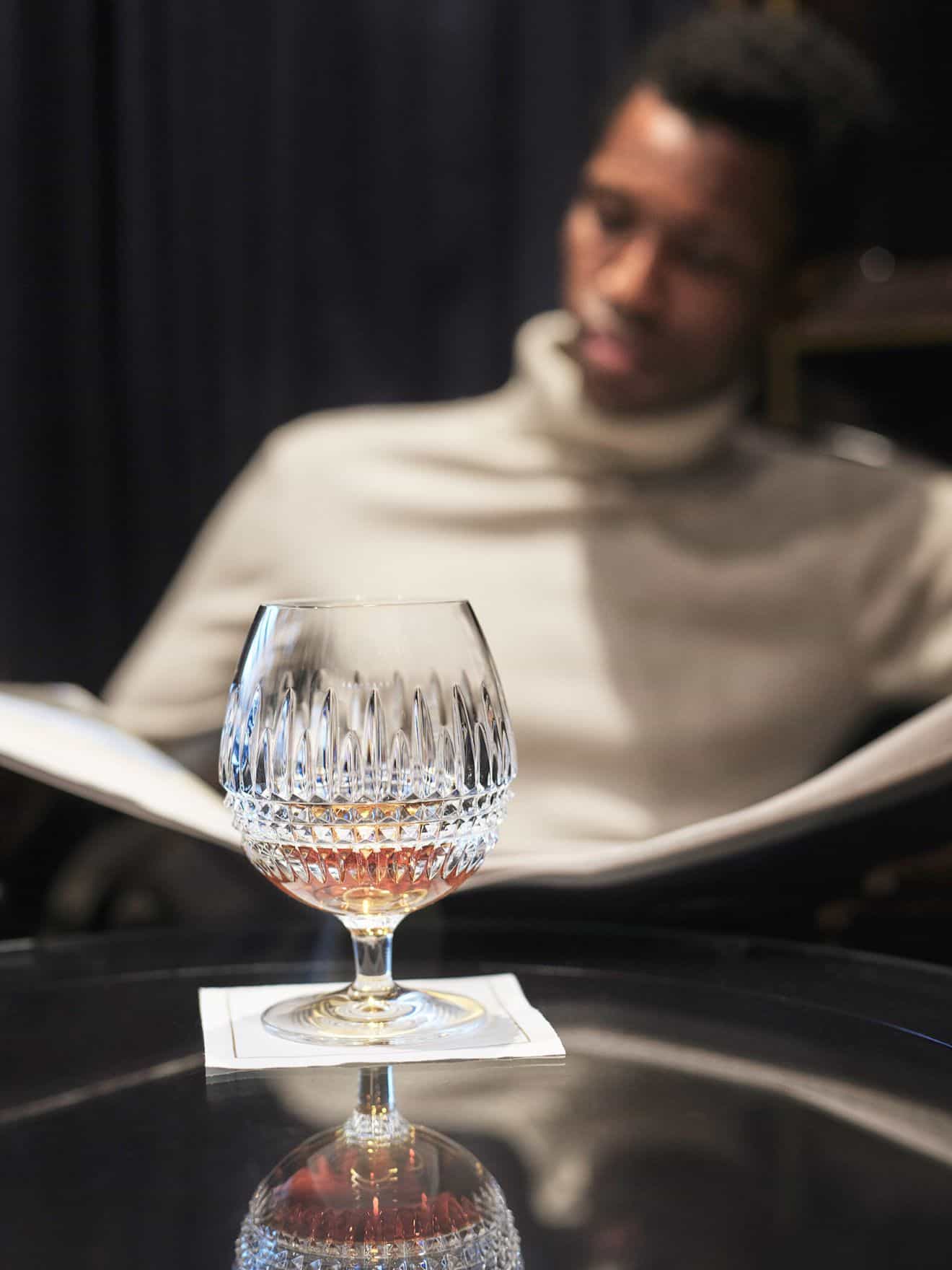 Man in background reading paper with drink on table