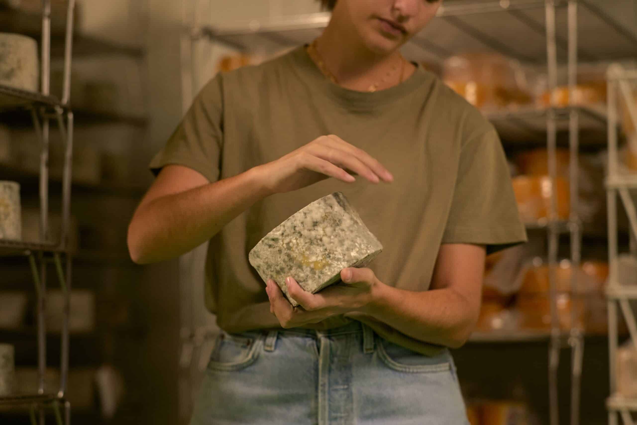 Person holding a wheel of cheese