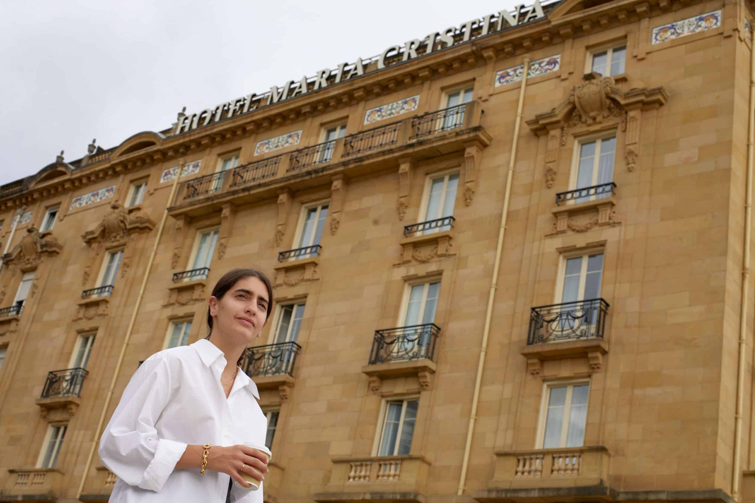 Woman in front of hotel holding a cup of coffee