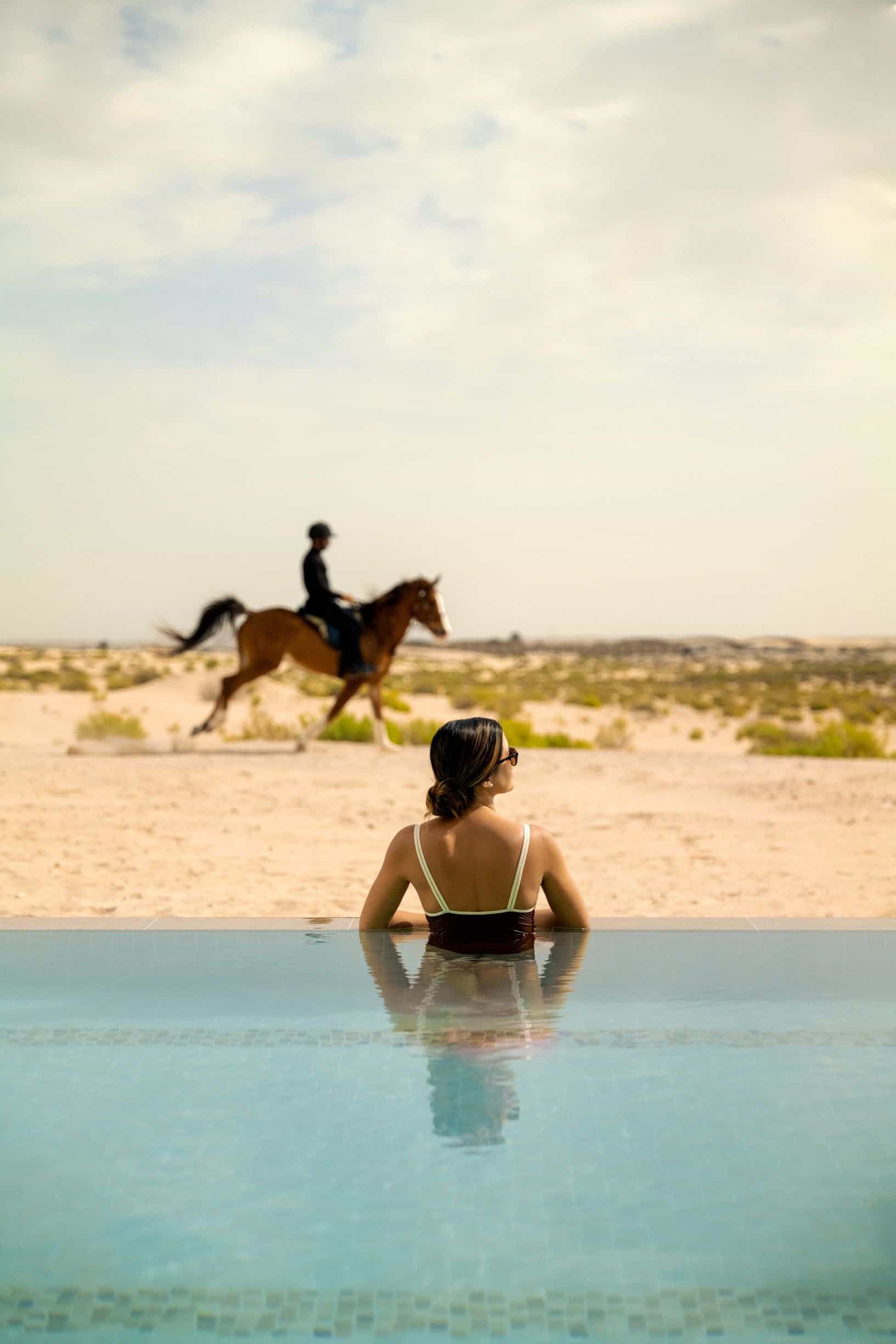 woman in pool looking at man on horse