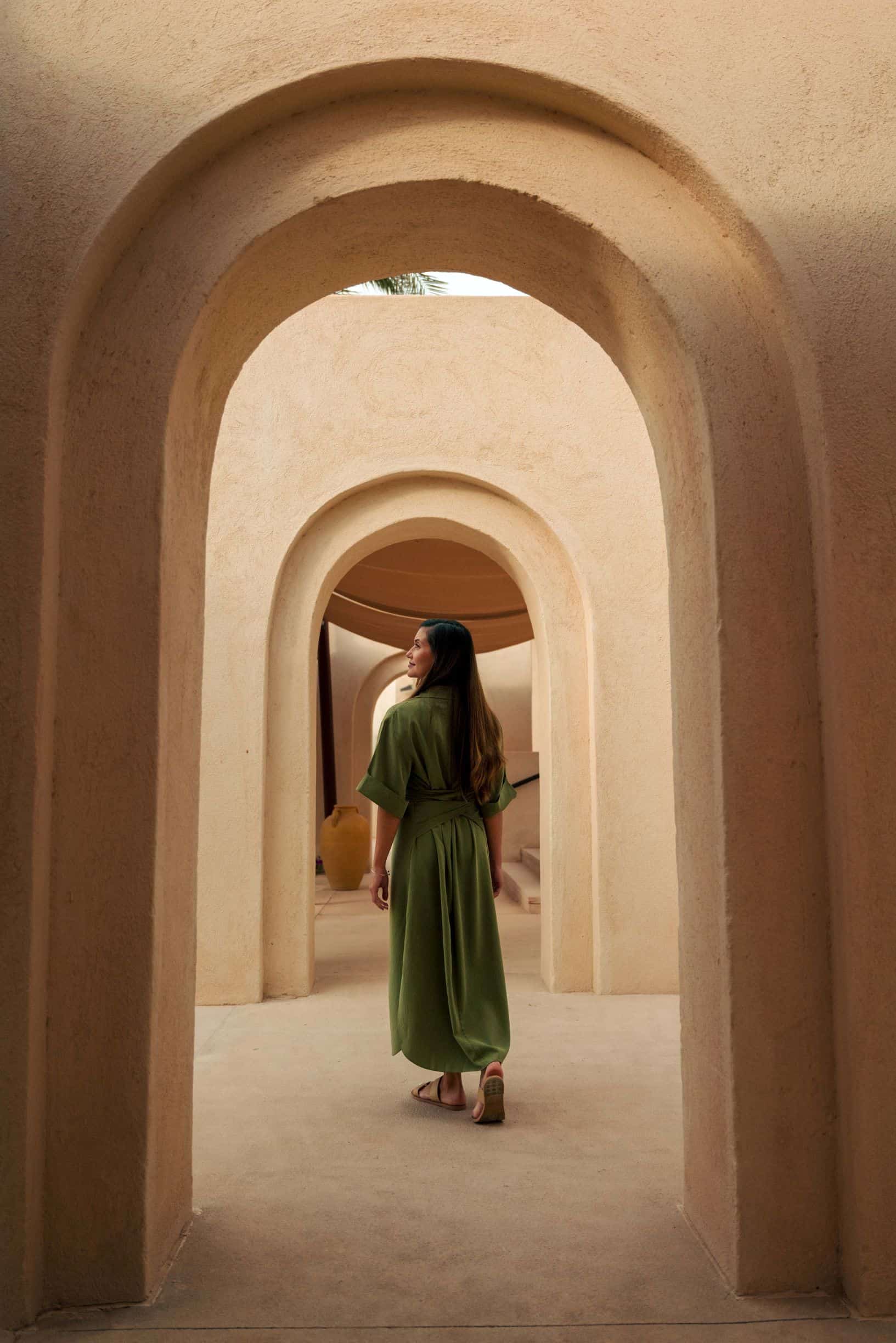 A woman standing below arched doorways.