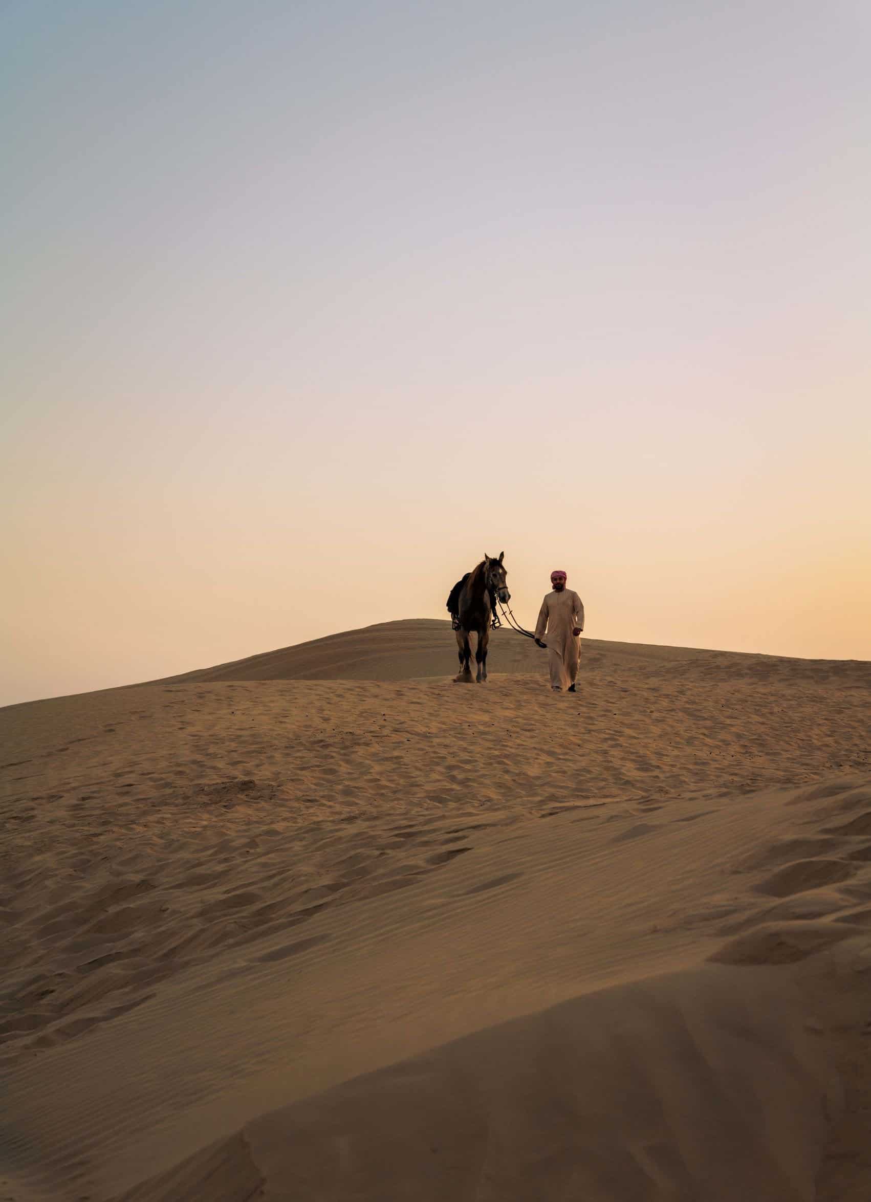 man walking horse in desert